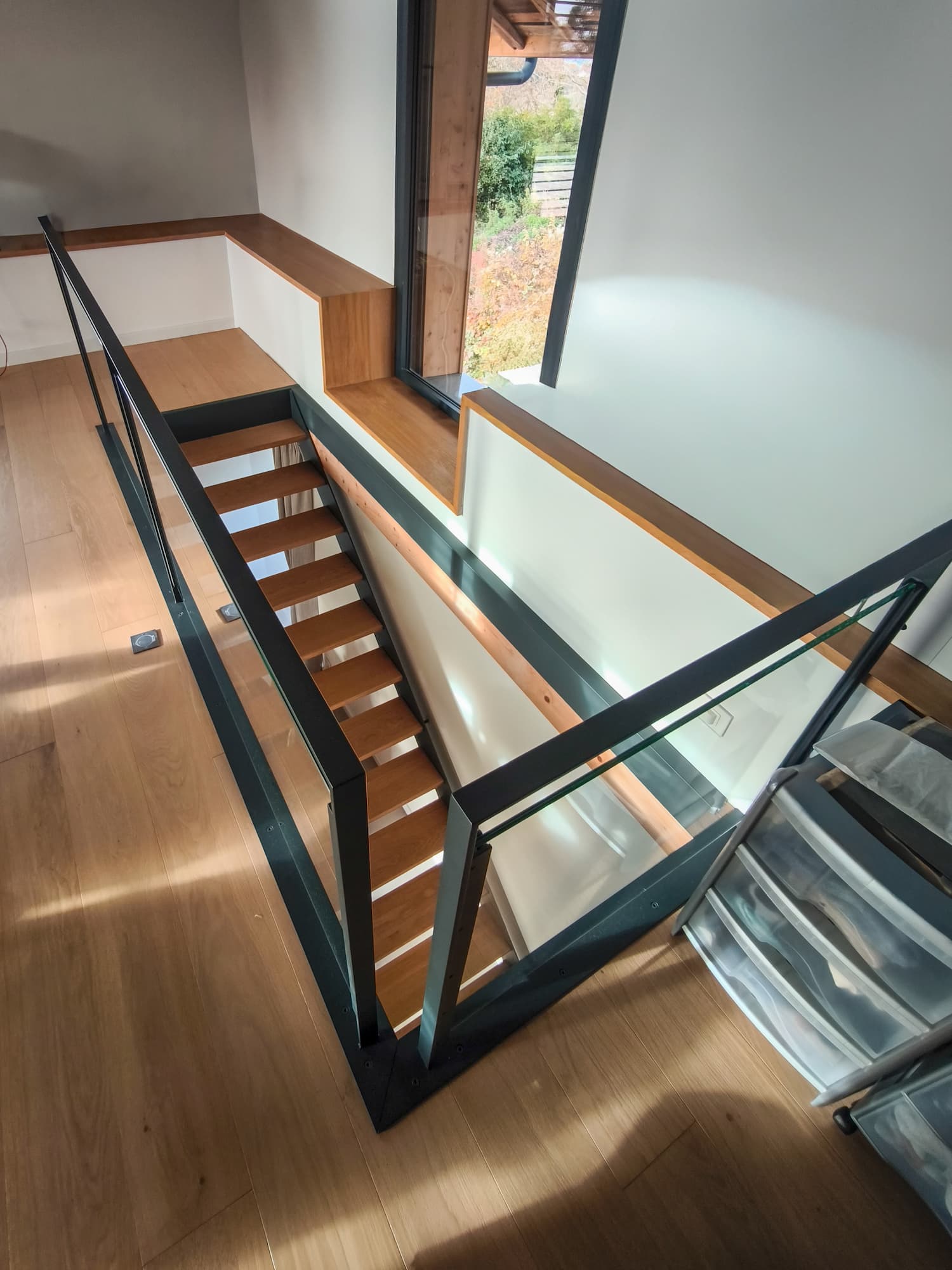Détail d’un escalier en acier et bois avec garde-corps en verre